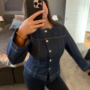 Mörkblå jeansjacka - Snygg mörkblå jeansjacka med knappar framtill. Jackan har en figursyd(prislappen är kvar)