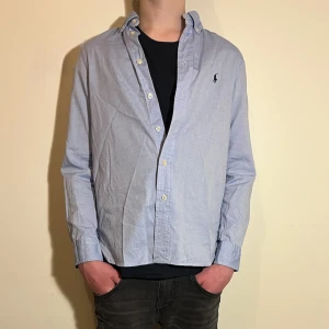 Ralph Lauren skjorta - Snygg blå skjorta från Ralph Lauren i slim fit.  Perfekt för en stilren look med den klassiska loggan broderad på bröstet. Jag skickar helst med PostNord. 