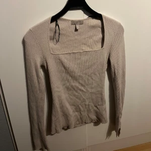 Beige ribbad tröja från H&M - Säljer en stilren beige ribbad tröja från H&M. Tröjan har en fyrkantig halsringning och långa ärmar, perfekt för en avslappnad look. Passar bra till både jeans och kjol. Den sitter även fint på kroppen då den framhäver kurvorna snyggt! 