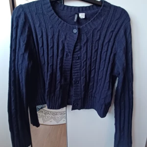 Stickad kofta  - Säljer en mörkblå kofta från H&M💕 Den är stickad med ett snyggt flätmönster och har knappar framtill med en croppad passform 💕Perfekt för kyligare dagar! Nästan aldrig använd! 