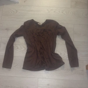 Brun kofta från PompoLux - Säljer en brun kofta från PompoLux med knappar framtill. Den har långa ärmar och en ribbad kant vid halsen. Perfekt för kyligare dagar. Storlek XS. 