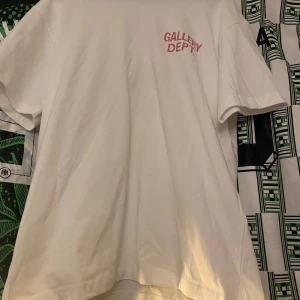  t-shirt från Gallery Dept. - Snygg vit t-shirt från Gallery Dept. med röd text på bröstet och ryggen. Perfekt för en avslappnad stil.