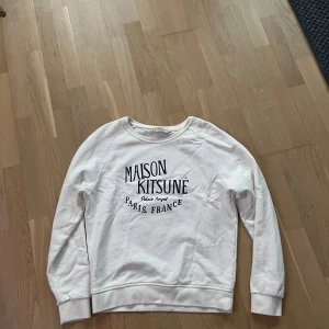 Vit sweatshirt från Maison Kitsuné - Säljer en stilren vit sweatshirt från Maison Kitsuné som jag inte använder längre. Skick:9/10. Finns inga  defekter på tröjan, den e som ny. Hör av er om ni har frågor!