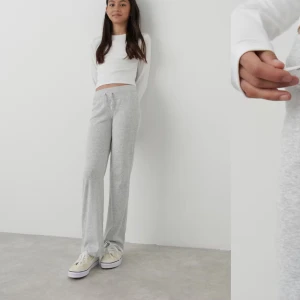 Grå mjukisbyxor - Snygga och bekväma grå mjukisbyxor med låg midja och rak passform. Perfekta för en avslappnad stil. Byxorna har snörning i midjan för justerbar passform.