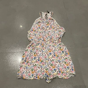 Blommig outfit från h&m - Söt blommig outfit från h&m med ett färgglatt mönster i rosa, blått och grönt. Den har en halterneck-design och är ärmlös, perfekt för varma dagar. Den har en öppen design på baksidan så man ser ryggen. Skriv privat för fler bilder eller frågor :) 
