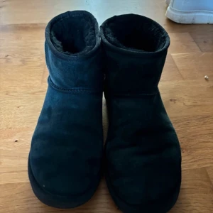 Svarta boots i mocka - Säljer ett par svarta uggs. De är varma och perfekta för kyligare dagar. Enkel design utan snörning eller dragkedja.