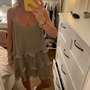 Beige volangklänning - Säljer en söt beige klänning med volanger och smala axelband. 