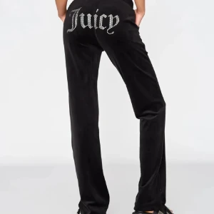 Svarta velourbyxor från Juicy Couture - Snygga svarta velourbyxor från Juicy Couture med glittrande textdetalj på baksidan. 