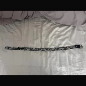 Svart bälte med silverdetaljer - Snyggt svart bälte dekorerat med glittriga silverdetaljer. Perfekt för att ge en extra touch till din outfit. Bältet har ett klassiskt spänne i silverfärg. 80cm