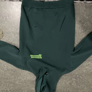 Grön Dungeons & Dragons hoodie - Cool grön hoodie med Dungeons & Dragons-tryck på bröstet och ett stort, färgglatt motiv på ryggen. Perfekt för fans av spelet! Den har en klassisk känguruficka och huva.