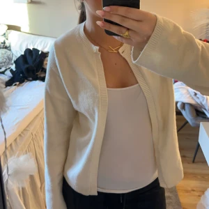 Beige kofta - Säljer en stilren beige kofta med rund halsringning. Perfekt för lager-på-lager och passar till många olika outfits. Koftan har långa ärmar och en enkel design som gör den mångsidig.