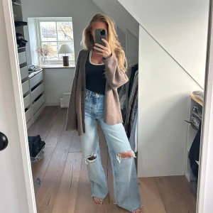 Ljusa jeans med slitningar från Zara - Snygga ljusblå jeans från Zara med slitningar på knäna. De har en hög midja och en avslappnad, wide fit-stil. Perfekta för en trendig och avslappnad look.