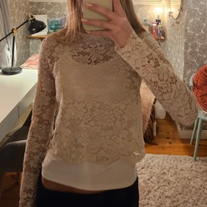 Beige spetströja från Gina Tricot - Säljer en kortare beige spetsblus från Gina Tricot i storlek XS. Blusen har långa ärmar och ett vackert blommigt mönster.💞🌸