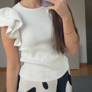  ribbad topp med volangdetalj ZARA - Snygg vit ribbad topp med en unik volangdetalj på ena axeln.  Köpt från zara