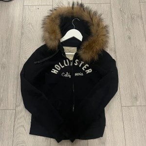 Svart hoodie med päls från Hollister - Säljer en svart/ väldigt mörk blå hoodie från Hollister med päls luva! Fint skick! Perfekt för dig som har 2000s stil då den är från 2000-talet! ❤️ säljer den då jag inte gillar hur den sitter på mig ❤️