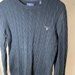 Blå kabelstickad tröja från GANT - Snygg blå kabelstickad tröja från GANT med rund halsringning. Storlek M. Säljs för billigt pris. Vid fundering kontakta gärna oss 