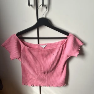 Rosa ribbad topp från Tommy Hilfiger - Säljer en söt rosa ribbad topp från Tommy Hilfiger. Toppen har en offshoulder-design och är croppad med vågiga kanter. Perfekt för en trendig look!