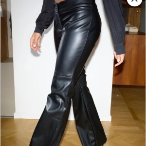 Svarta skinnbyxor - Snygga svarta skinnbyxor med låg midja och bootcut-stil. Perfekta för en trendig look med en tight passform som framhäver figuren. Byxorna har en dragkedja framtill och är tillverkade i ett glansigt material som ger en lyxig känsla. Från Nelly med lappar kvar. Storlek S / 36.