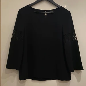 Svart blus från Vila - Svart blus från vila med vid trekvart skärm och spetsdetaljer.