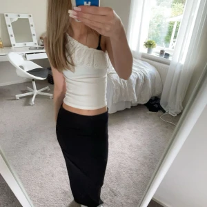 Vit offshoulder topp med spetsdetaljer - Snygg vit offshoulder topp med spetsdetaljer längs kanten. Perfekt för en somrig look. Toppen har en tight passform och är tillverkad i ett mjukt material.
