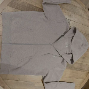 Grå hoodie från Ralph Lauren - Säljer en stilren grå hoodie från Ralph Lauren med dragkedja och luva. Tröjan har långa ärmar och en liten broderad logotyp på bröstet. Perfekt för en avslappnad look. Pris kan diskuteras vid snabb affär!