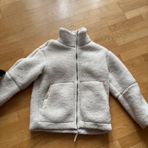 Vit teddyjacka H&M - Mysig vit teddyjacka med dragkedja och stora fickor framtill. Använder den tyvärr inte då jag har en annan! Slutsåld på H&M s hemsida! Storlek XS