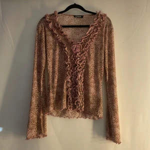 Leopardmönstrad blus från DNA - Säljer en rosa typ leopardmönstrad blus från DNA med volangdetaljer längs halsringningen och framsidan. Blusen har långa ärmar och en v-ringad design. Perfekt för att lägga till lite mönster i garderoben!💗pris kan oftast diskuteras 