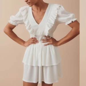 Vit klänning med volanger - Säljer Charmig vit klänning med v-ringning och volangdetaljer från Gina tricot. Den har korta ärmar och en smickrande passform med elastisk midja. Perfekt för sommarens alla tillfällen. Den är endast använd 1 gång och testad. Skriv om ni har frågor💗