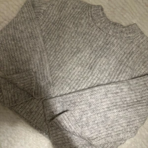 Grå stickad tröja - Mysig grå stickad tröja med ribbade muddar vid ärmslut och nederkant. Storlek S och köpt på Ginatricot, aldrig använd