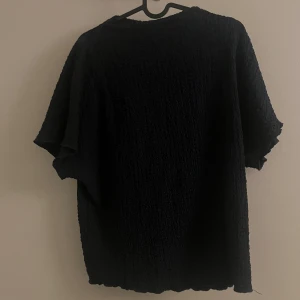 Marinblå texturerad topp - Snygg marinblå topp med texturerad yta och korta ärmar. Perfekt för en stilren look. Passar bra till både jeans och kjol.