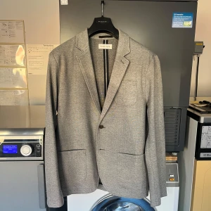 Grå kavaj från pier one - Grå kavaj från pier one i ett mjukt stretch material,  säljer nu denna kavaj då den känns lite för liten för mig, storleken är XL men sitter mer som en L, den har någon typ av fläck på höger axel oklart vad det är dock men annars i perfekt skick då jag bara använt den ett fåtal gånger hör gärna av er ifall ni har frågor eller vill ha fler bilder!