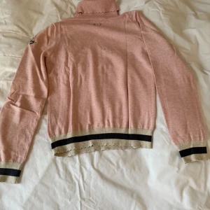 Rosa polotröja från Odd Molly - Säljer en söt rosa polotröja från Odd Molly i 100% bomull. Tröjan har långa ärmar och ribbade detaljer vid ärmslut och nederkant med grå rand.