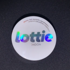 Power Foil Metallic Ögonskugga från Lottie London - Snygg och glittrig ögonskugga i nyansen 'Unphased' från Lottie London. Denna power foil metallic ögonskugga ger en intensiv och skimrande look. Perfekt för att skapa en dramatisk effekt med sin kopparfärgade ton.