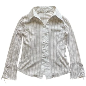 Meshskjorta från Kailiailila - Vit skjorta med krage, svagt färglada sömdetaljer (se bilder), metallspännen och knytdetalj vid vid änden av armarna 🤍Jag brukar ha strl XS/S för referens! 