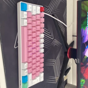 Flerfärgat mekaniskt tangentbord från NGS - Säljer ett mekaniskt tangentbord från NGS med en färgglad design. Tangentbordet har rosa, vita, blå och gröna tangenter och en vit bas. Perfekt för gaming eller kontorsarbete. Ansluts via USB.