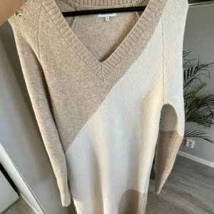 Beige stickad klänning från Bubbleroom - Säljer en mysig beige stickad klänning från Bubbleroom med ett stilrent mönster i ljusare nyanser. Klänningen är tjockt stickad och har en v-ringad hals och långa ärmar. Nypris 800.