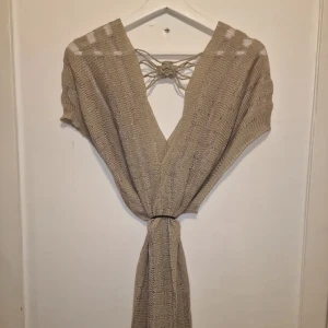 Stickad topp från Vila - Snygg stickad topp från Vila i nyansen caramel med knytning i ryggen och v-ringad design. Perfekt för en stilren look med en touch av elegans. 