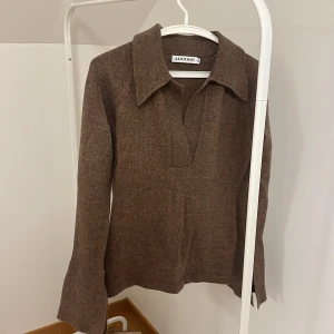 Brun stickad tröja från ADOORE - Säljer en snygg brun stickad tröja från ADOORE. Tröjan har en stilren design med långa ärmar och en djup v-ringning. Perfekt för kyligare dagar och ger en elegant touch till din outfit.