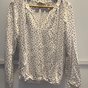 Benvit topp med svarta prickar - Endast provad (saknar prislapp) topp från House of Lola. Jätteskönt tyg som ger fint fall.