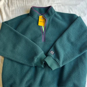 Grön fleece tröja från Levi's - Säljer en mysig grön fleece tröja från Levi's med halv dragkedja i storlek M. Aldrig använd, lapp kvar. 