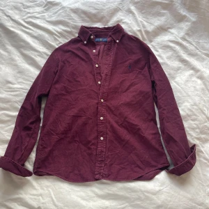Vinröd skjorta från Ralph Lauren - Skit snygg vin röd Ralph lauren skjorta i jätte tätt Manchester material, väldigt bra skick och perfekt för sommaren men även snygg under en cardigan.😊