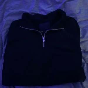 Svart half-zip med dragkedja - Säljer en stilren svart half-zip med dragkedja. Perfekt för en avslappnad look. Den har en hög krage och är tillverkad i ett mjukt material för extra komfort. Från lager 157 nypris 300kr