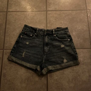 Mörkblå jeansshorts med slitningar - Snygga mörkblå jeansshorts med slitna detaljer och uppvikta kanter. Najs men inte min stil så därför jag säljer dem. Aldrig använda💙kostade 199kr men säljer dem för 77 för jag har inget kvitto 