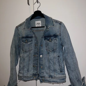 Jeansjacka från Zara - Snygg jeansjacka från Zara i en klassisk blå färg. Jackan har en normal passform med knappar framtill och två bröstfickor. Perfekt för vår och sommar!