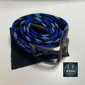 Flätat bälte från Wear Edge - Snyggt flätat bälte i blå och svarta nyanser från Wear Edge. Bältet har en stilren silverfärgad spänne och detaljer i brunt skinn. Perfekt för att ge en färgklick till din outfit. Riktigt snyggt och Grischigt om de är de man söker😀