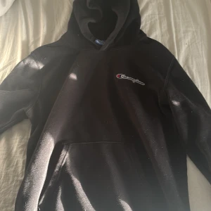 Svart hoodie från Champion - Säljer en klassisk svart hoodie från Champion. Den har en känguruficka framtill och en justerbar huva. Perfekt för en avslappnad stil. Den har inga snören då jag för länge sedan tagit ut dem då de passade bättre, storlek S. Säljer då jag inte har användning för den längre. Har en liten missfärgning vid halsen men syns knappt.   Pris går att diskutera vid snabb affär 🩷