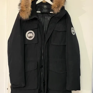 Svart parkajacka  - Säljer en svart parkajacka  i samarbete med October's Very Own. Jackan har en pälsfodrad huva och flera praktiska fickor. Perfekt för kalla vinterdagar.