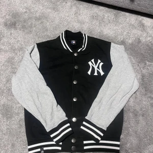 Svart och grå baseballjacka från Majestic - Snygg svart och grå baseballjacka från Majestic med New York Yankees-logga på bröstet. Den är i bra skick och söker man på nätet kan man hitta liknande allt från 750 kr till 2000 kr. Bara att skriva vid frågor och funderingar. 