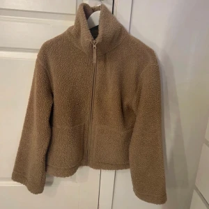 Beige teddyjacka från h&m - Mysig beige teddyjacka från H&M med dragkedja framtill. Perfekt för kyliga dagar med sin mjuka och varma design. Jackan har en hög krage och långa ärmar. Slutsåld på hemsidan💗