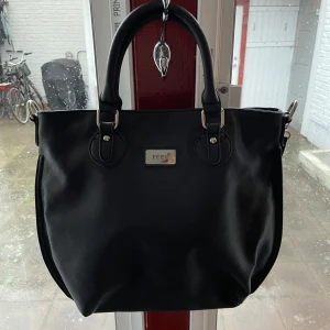 Svart axelväska från Feel - Snygg svart axelväska från Feel med leopardmönstrat foder. Väskan har både handtag och en justerbar axelrem för flexibilitet. Den är utrustad med dragkedja för säker förvaring och har en praktisk ficka på baksidan, även på insidorna av väskan! Aldrig använd!!!